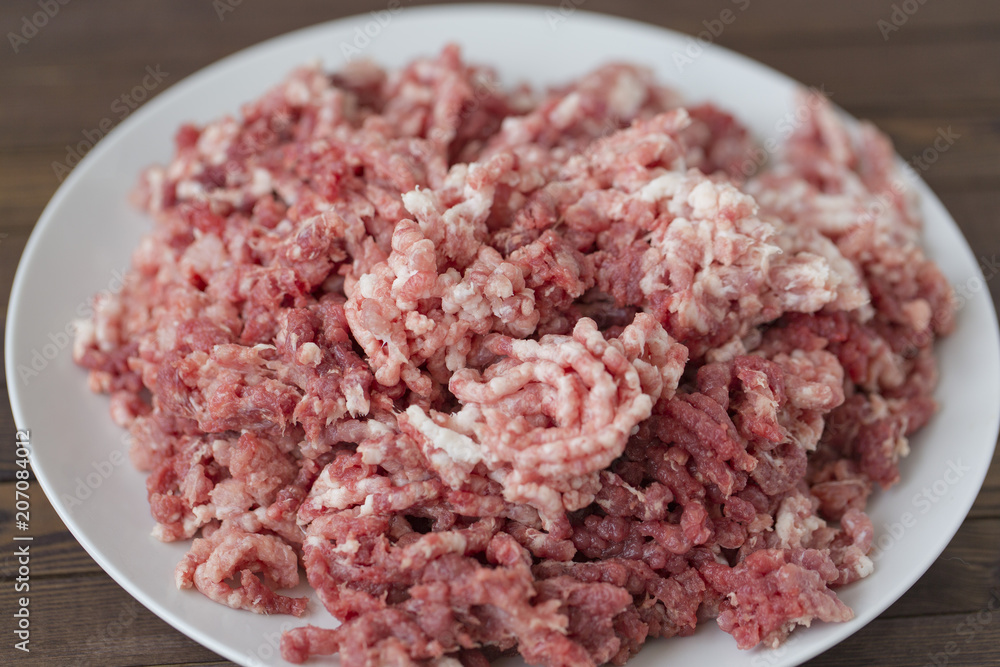 fresh raw minced beef in a plate close up on a rustic wooden table fresh raw minced beef in a plate close up on a rustic wooden table