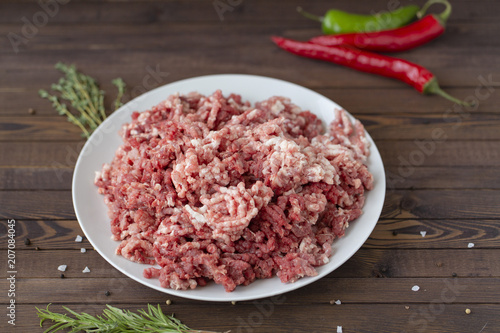 fresh raw minced beef in a plate close up on a rustic wooden table