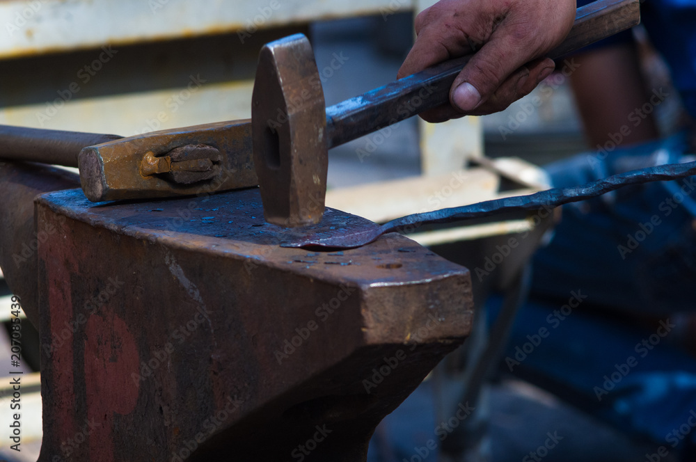 blacksmith performs the forging of hot glowing metal on the anvil blacksmith performs the forging of hot glowing metal on the anvil
