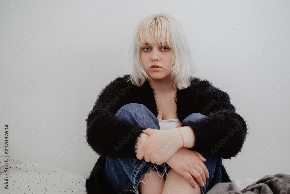 Depressed young blond woman sitting alone in her room. Mental problems with depression and bulimia. Depressed young blond woman sitting alone in her room. Mental problems with depression and bulimia.