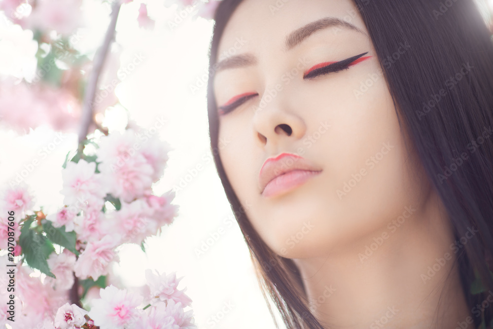Gorgeous fantasy girl face dreaming with closed eyes against nature beauty background. Perfect model with creative vivid makeup and pink lipstick on lips and traditional japanese hairstyle posing Gorgeous fantasy girl face dreaming with closed eyes against nature beauty background. Perfect model with creative vivid makeup and pink lipstick on lips and traditional japanese hairstyle posing
