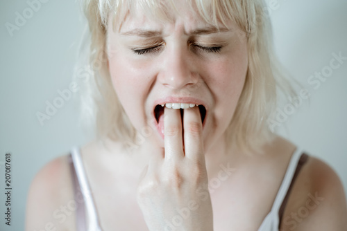 Portrait of young blond woman, annoyed, frustrated fed up sticking her finger in her throat. Mental disorders bulimia, addiction. photo