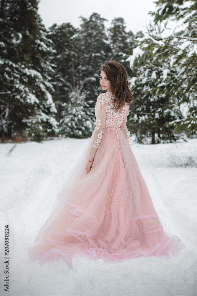 Girl in a beautiful pink dress in a winter forest Girl in a beautiful pink dress in a winter forest