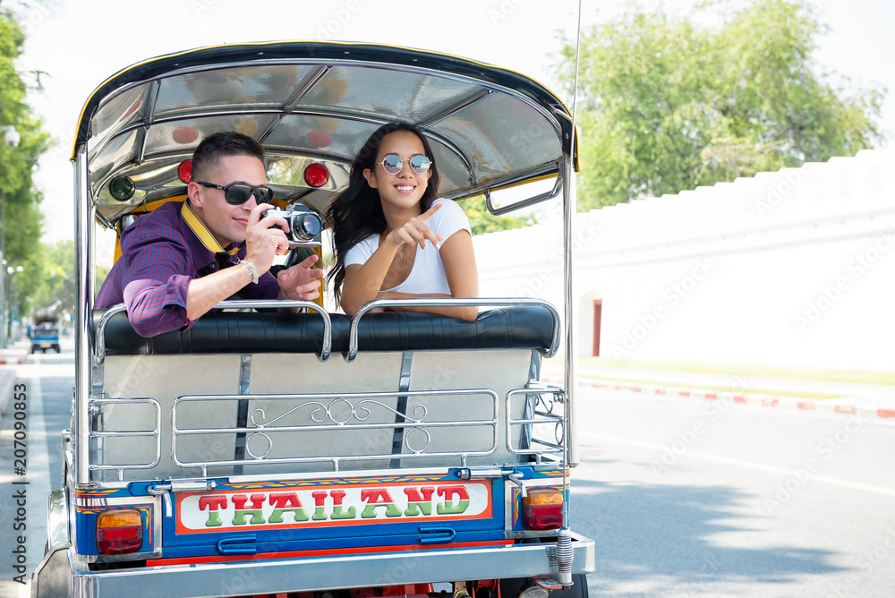 Obraz premium Young couple tourists traveling on local Tuk Tuk taxi in Bangkok, Thailand