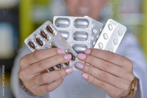 Female doctor hand hold pack of different tablet blisters at workplace.