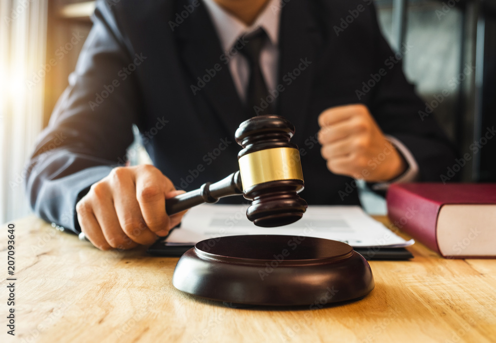 Justice and law concept.Male judge in a courtroom with the gavel,working with,digital tablet computer docking keyboard,eyeglasses,on wood table Justice and law concept.Male judge in a courtroom with the gavel,working with,digital tablet computer docking keyboard,eyeglasses,on wood table