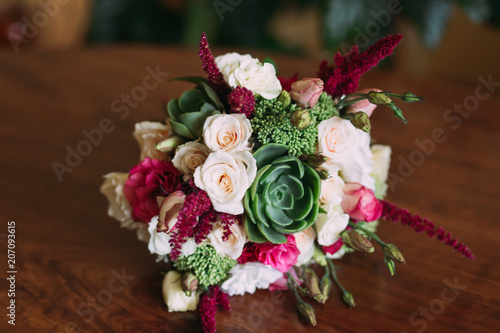 beautifully decorated wedding bouquet of roses lying on a wooden surface