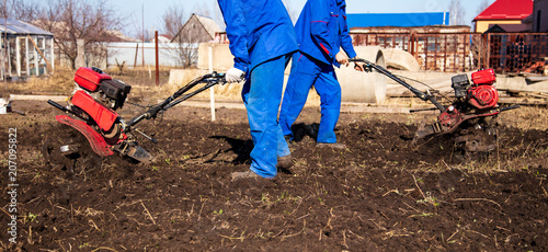 Worker with a machine cultivator digs the soil in the garden