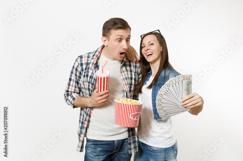 Young couple, woman and man watching movie film on date holding bucket of popcorn plastic cup of soda or cola and bundle of dollars cash money isolated on white background. Emotions in cinema concept.