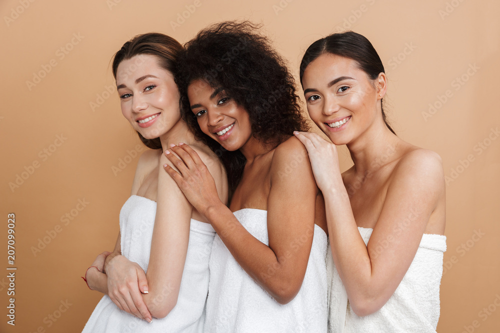 Side view of three pleased naked women wearing in towels Side view of three pleased naked women wearing in towels