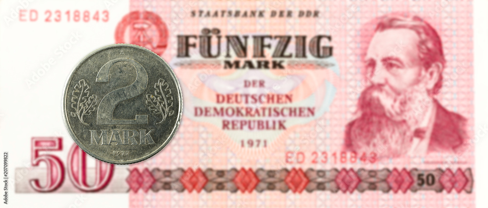 2 mark coin against historic 50 east german mark bank note