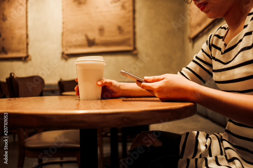 lifestyle background woman holding coffee glass and using mobile phone sitting in restaurant with copy space. image for food, person, technology, portrait concept