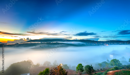 Dawn on plateau in morning with colorful sky, while sun rising from horizon shines down to small village covered with fog shrouded landscape so beautiful idyllic countryside Dalat plateau, Vietnam