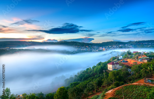Dawn on plateau in morning with colorful sky  while sun rising from horizon shines down to small village covered with fog shrouded  landscape so beautiful idyllic countryside Dalat plateau  Vietnam