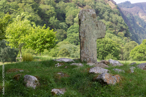 Legendary ancient celtic cross surrounded by stones against moutain range