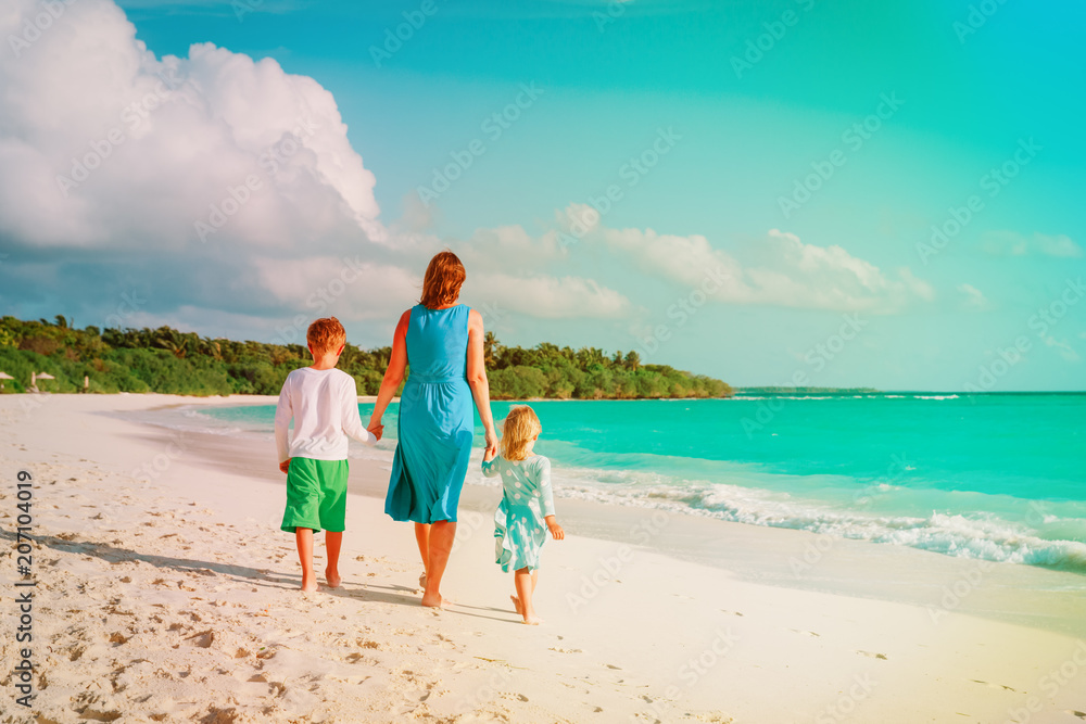 mother with kids- boy and girl- walk on beach