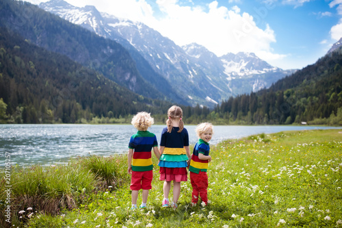 Children hiking in flower field at mountain lake