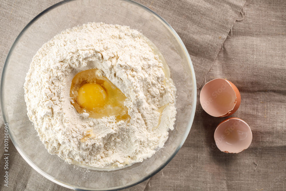 preparation of dough for flat bread. broken egg and flour in a glass bowl preparation of dough for flat bread. broken egg and flour in a glass bowl
