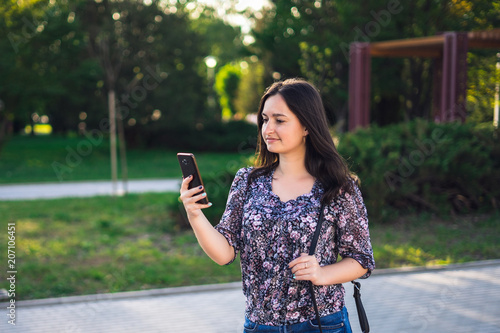 Young woman walking with phone in park