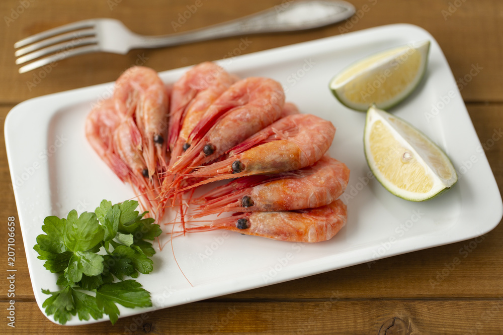 Cooked shrimps on plate with lemon, salt, pepper. Seafood appetizer. Cooked shrimps on plate with lemon, salt, pepper. Seafood appetizer.