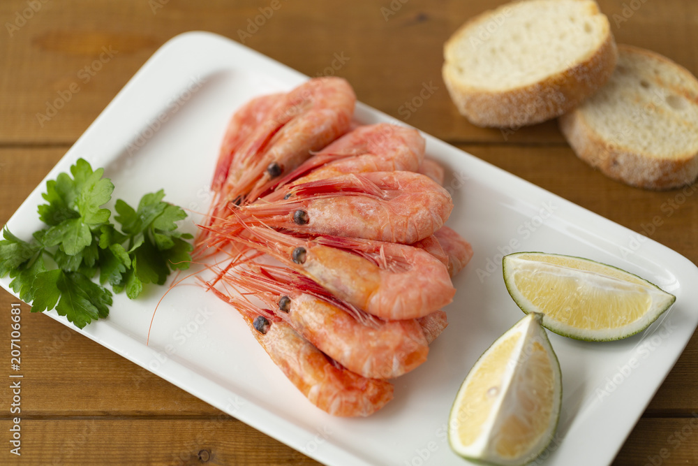Cooked shrimps on plate with lemon, salt, pepper. Seafood appetizer. Cooked shrimps on plate with lemon, salt, pepper. Seafood appetizer.