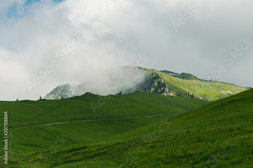 Beautiful mountain landscape with green hills on a cold foggy day, with sky and clouds