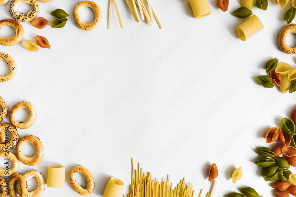 Background with different types of raw pasta and pretzels. Flatlay