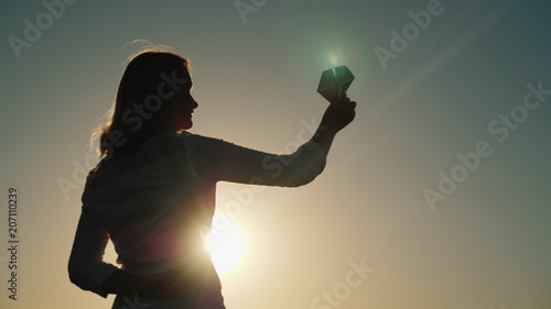 A middle-aged woman is playing with a paper airplane at sunset. Dreams and childhood concepts