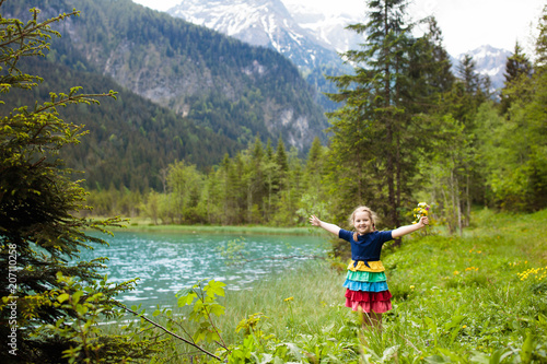 Child hiking in flower field at mountain lake