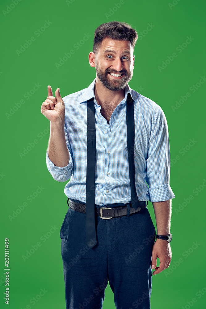 The young attractive man looking suprised isolated on green The young attractive man looking suprised isolated on green