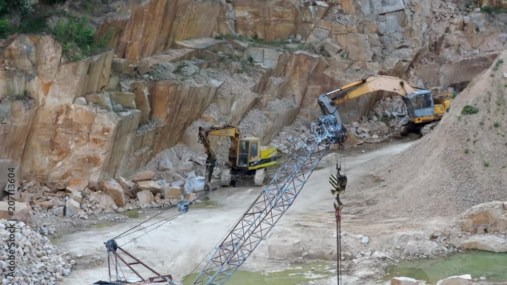 Mining in the granite quarry. Working mining machines - old crane and digger. Mining industry. Mining in the granite quarry. Working mining machines - old crane and digger. Mining industry.