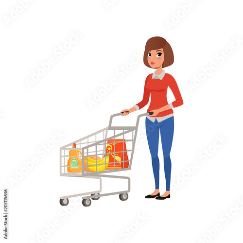 Cartoon woman standing near supermarket cart with products. Shopping in grocery store. Young girl in blouse and jeans. Flat vector design