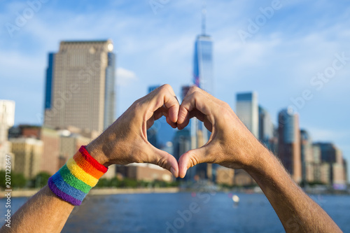 Photography Hands wearing pride rainbow wristband making heart symbol