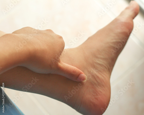 Feet massage, massaging ankle in pain.