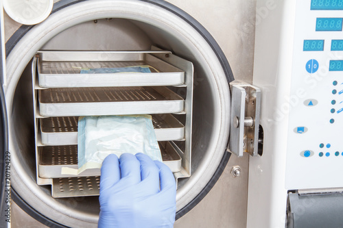 Nurse is sterilizing bandages in autoclave at dental office photo