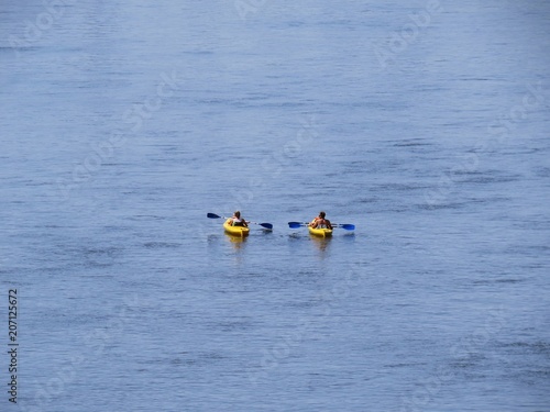 Family Kayaking on Two Kayaks on River at Sun