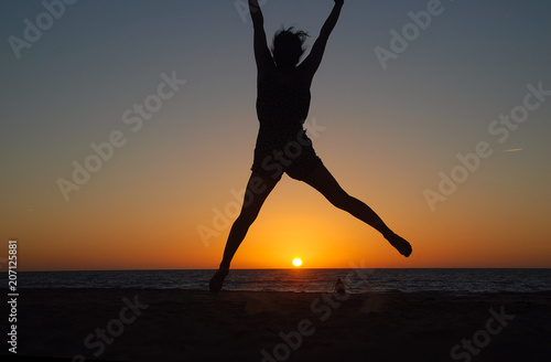 Foto CHICA SALTANDO EN LA PLAYA AL ATARDECER