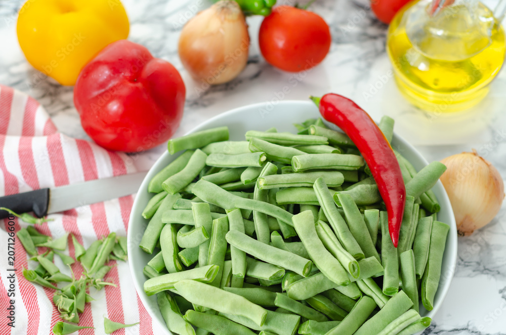 Green beans in the white plate on grey and white background. Green beans in the white plate on grey and white background.