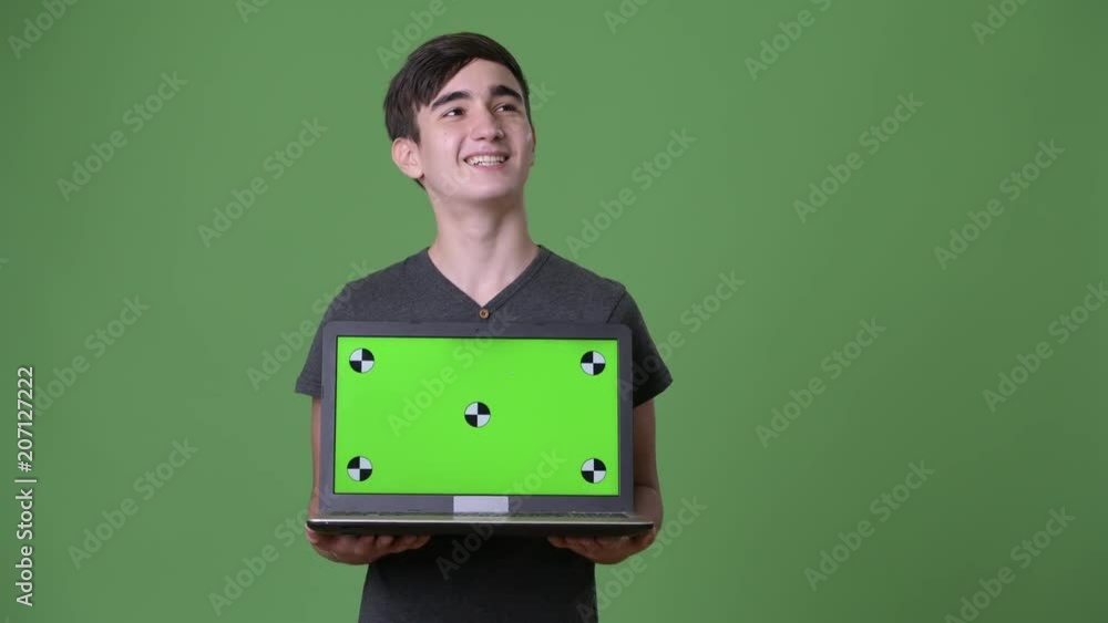 Young handsome Iranian teenage boy against green background Young handsome Iranian teenage boy against green background