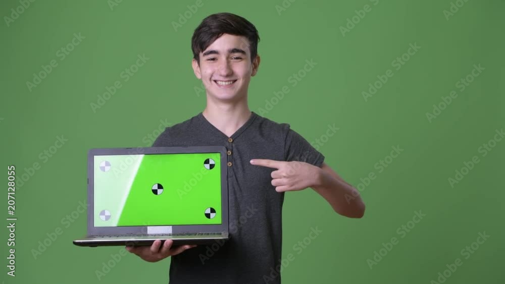 Young handsome Iranian teenage boy against green background Young handsome Iranian teenage boy against green background
