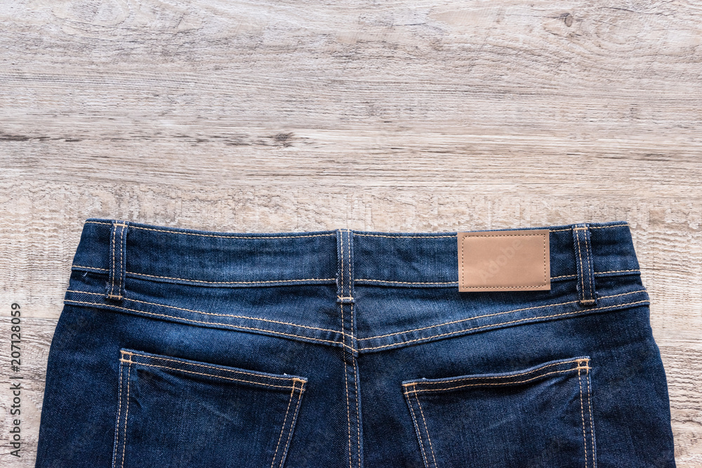 Blue jeans on wood background with leather label. Blue jeans on wood background with leather label.