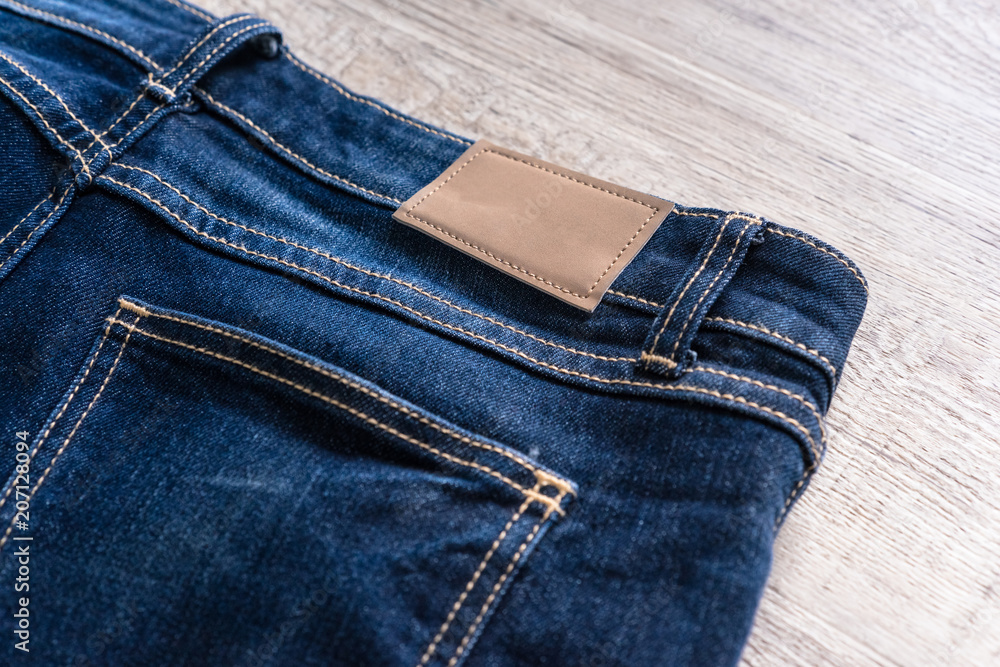 Blue jeans on wood background with leather label. Blue jeans on wood background with leather label.