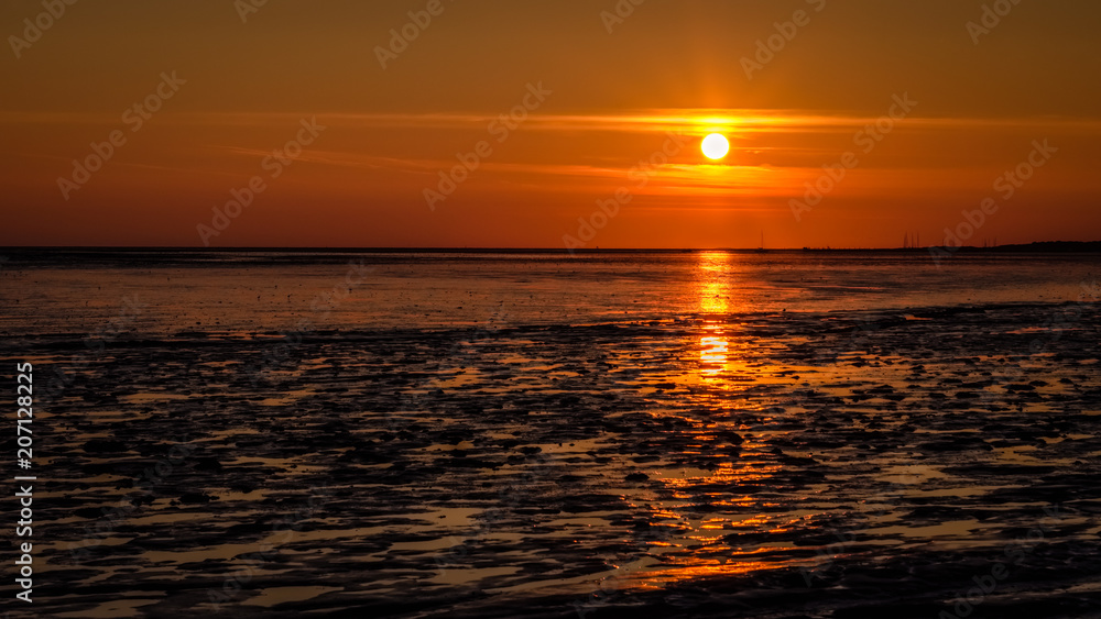 The sky gets darker and turns orange as the sun has almost set on the shores of the Wadden Island of Schiermonnikoog (Friesland, the Netherlands) on a September evening.