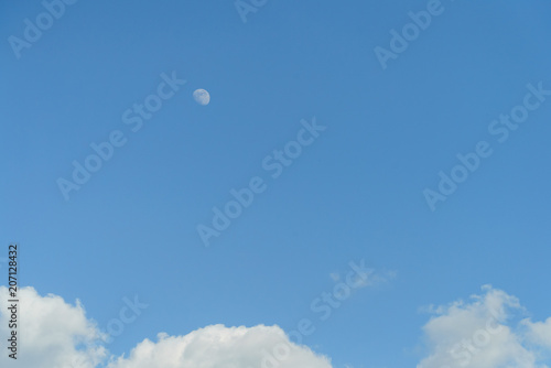 Moon during the day, blue sky with clouds
