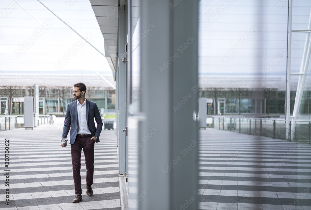 Young businessman on the go at building with glass facade Young businessman on the go at building with glass facade