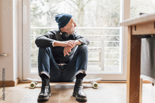 Cool senior man sitting on ground, looking out of window photo