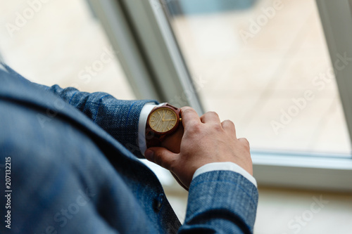 Top view of a man's hands in a suit looking at a wrist watch. Businessman is checking time on his modern wrist watch. Top view. Space for text.