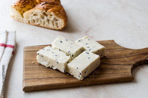 Turkish Feta Cheese with Black Cumin (Sesame) Seeds on Wooden Surface with Knife. photo