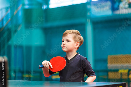 little child plays table tennis in the gym