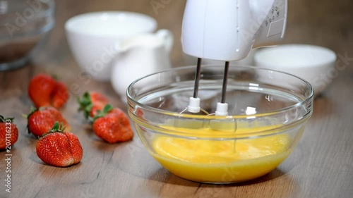 Beaten Eggs with Mixer Whisks in Bowl. photo